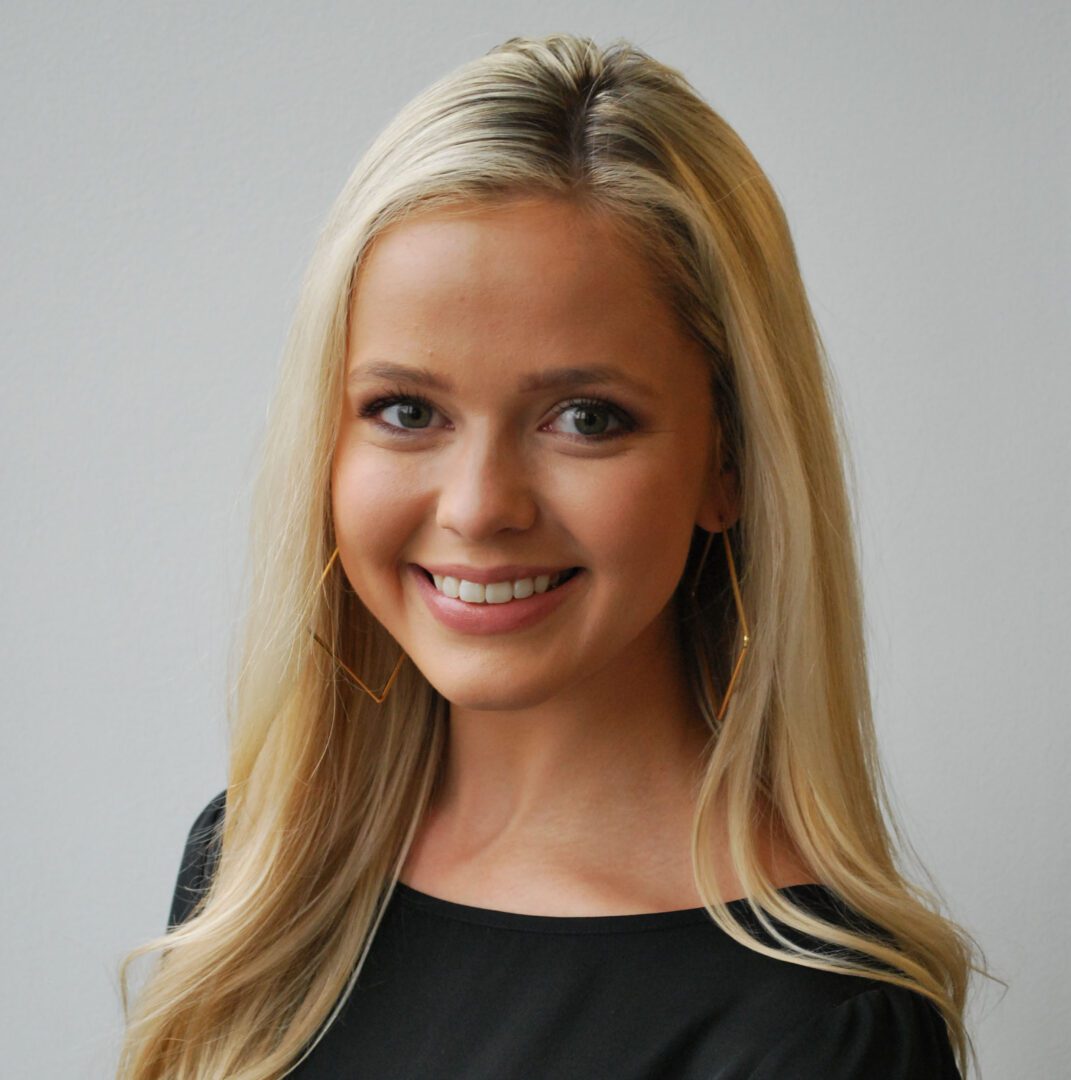 A woman with long blonde hair wearing black.
